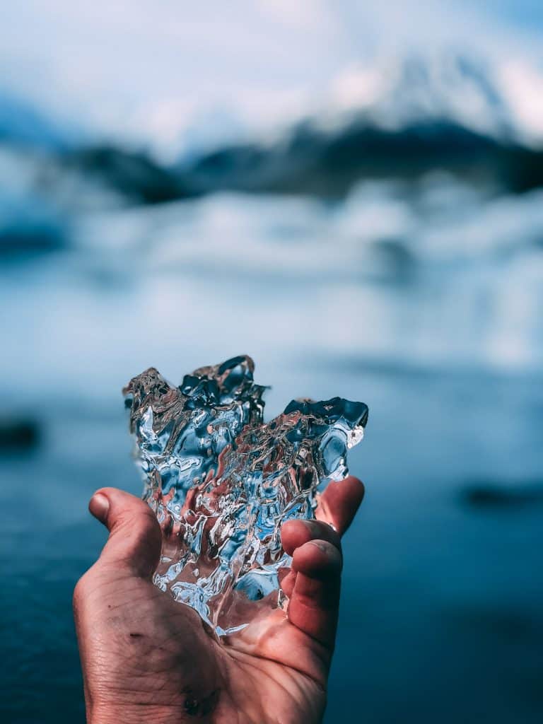 Una persona sostiene la mejor protección solar facial frente a un lago.