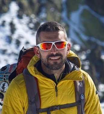Un hombre con gafas de sol que proporcionan una mejor protección solar facial en la cima de una montaña nevada.