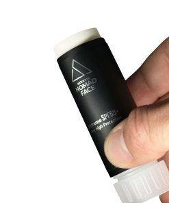 stick spf50+ mejor-proteccion-solar-facial Una mano sosteniendo un tubo negro de protector solar Nomad Face con factor de protección 50. El tubo está parcialmente abierto, mostrando la tapa blanca.