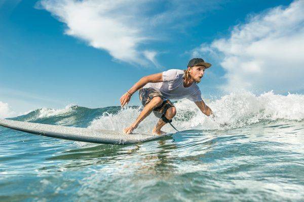 Protegido con una buena crema solar surf Hombre surfeando una ola en un día despejado, intensamente concentrado mientras se balancea sobre su tabla de surf.