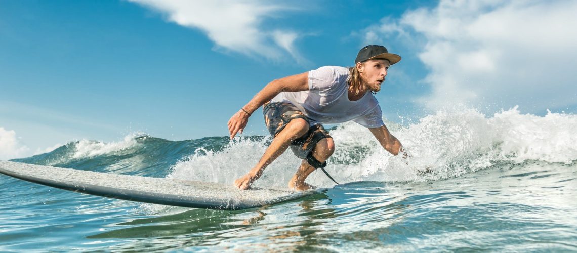 Protegido con una buena crema solar surf Hombre surfeando una ola en un día despejado, intensamente concentrado mientras se balancea sobre su tabla de surf.